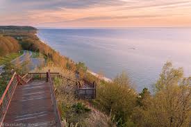 Forested cliffs sheltering a rocky Lake Michigan shoreline scattered with sun-bleached driftwood.