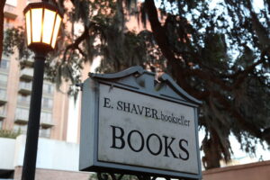 A cozy, wood-paneled nook hidden upstairs in a historic bookstore, lined with antique globes, leather-bound classics, and ladder-access shelves.