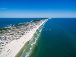 Wide, undeveloped shoreline near a historic Civil War fort, featuring surf-washed sands and flocks of seabirds soaring overhead.