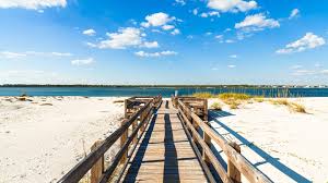 A protected stretch of white sand in Gulf Islands National Seashore, with shallow waves and trails through coastal wetlands.