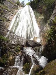 100-foot waterfall cascading through a lush redwood canyon, with remnants of 19th-century limekiln ruins nearby