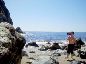 Dramatic rocky inlet with a historic timber tunnel, turquoise tidal pools, and steep canyon walls draped in succulents.