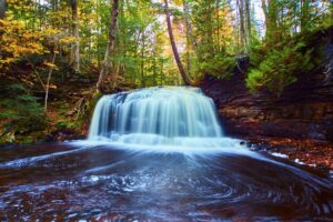 Remote cascades tumbling through a rocky canyon in Michigan’s wilderness, surrounded by ancient pine forests and rugged cliffs along the Rock River.