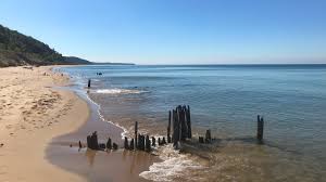 Steep dune trails descending to a quiet Lake Michigan beach surrounded by wooded bluffs.