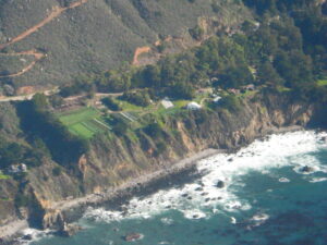 Cliffside mineral springs overlooking the Pacific Ocean, with steam rising from natural rock baths at dawn.