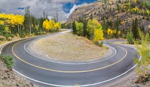 Winding cliffside route through the San Juan Mountains, with hairpin turns and panoramic views of red-rock gorges.