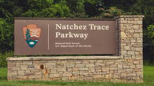 Historic Natchez Trace Parkway in Illinois, featuring a tree-lined road with fall foliage and a serene driving route.