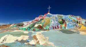 A sprawling, hand-painted desert monument with bright colors, flowers, and religious messages built from adobe and reclaimed materials.