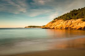 Stunning view of Sand Beach in Acadia National Park, surrounded by rocky cliffs and lush green forests.