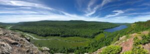 Scenic view of Porcupine Mountains Wilderness State Park in Michigan with vibrant fall foliage, rugged hills, and crystal-clear lakes.