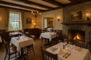 Cozy Vermont restaurant with rustic wooden beams, stone fireplace, and tables set for fine dining